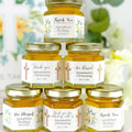 Stack of honey jars with personalized labels against a floral background