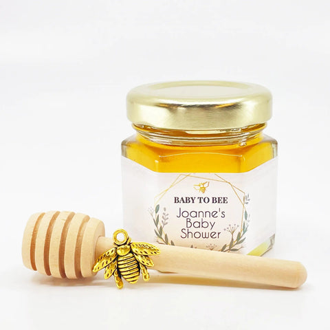 Jar of honey with a gold lid and wooden honey dipper on a white background
