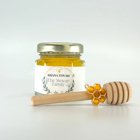 Jar of honey with a honey dipper on a white background