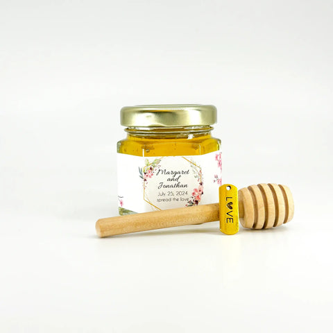 Jar of honey with a floral label and wooden honey dipper on a white background