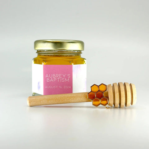 Jar of honey with a personalized label and a wooden dipper on a light gray background