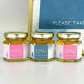 Three small hexagonal jars with personalized labels on a white surface.