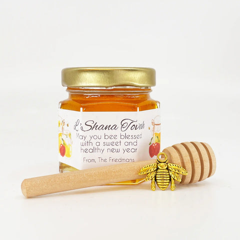 Jar of honey with a gold lid and wooden dipper on a white background