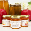 Jars of honey with Rosh Hashanah labels on a white background with apples and flowers.