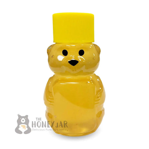 Yellow honey bear bottle with a yellow cap on a white background, featuring 'The Honey Jar' logo.