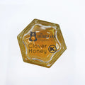 Hexagonal honey container with 'The Honey Jar' branding and kosher label on a white background
