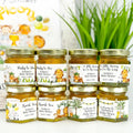 Jars of honey with personalized baby shower labels on a white surface with a blurred background