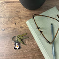 Keys with a bear keychain, glasses, and pen on a book on a wooden surface