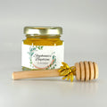 Jar of honey with a personalized label and wooden honey dipper on a light gray background