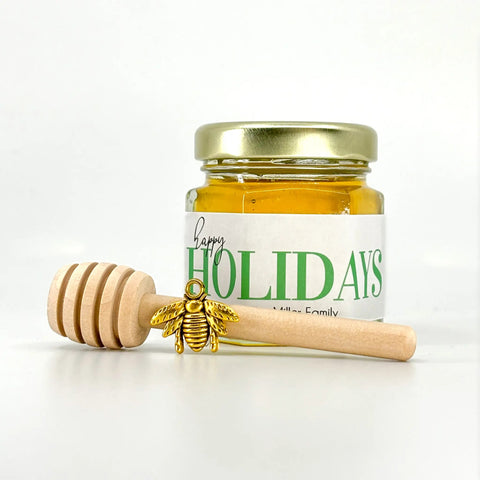 Jar of honey with a gold lid and wooden honey dipper on a white background