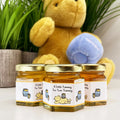 Three jars of honey with a teddy bear in the background
