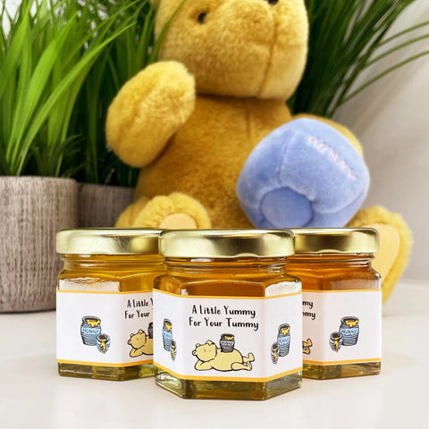 Three jars of honey with a teddy bear in the background