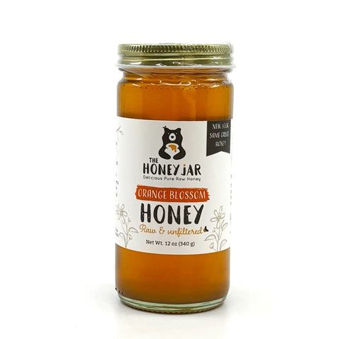 Jar of orange blossom honey with a label on a white background