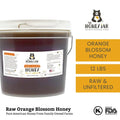 Bucket of raw orange blossom honey with The Honey Jar branding on a white background