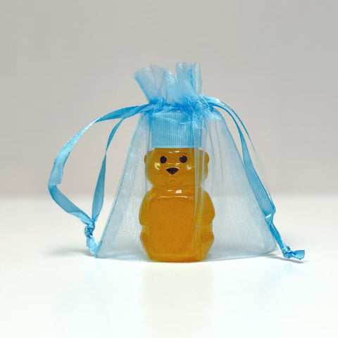 Honey bear in a blue organza bag on a light gray background