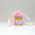 Jar of honey in a pink organza bag with a personalized label on a white background