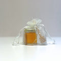 Jar of honey with a honey dipper inside a transparent white drawstring bag on a white background