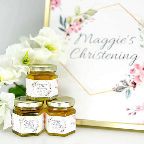 Jars of honey with floral labels next to a decorative sign 