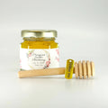 Jar of honey with a personalized label and wooden honey dipper on a white background