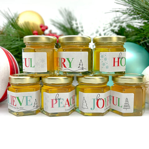 Jars of honey with Christmas-themed labels on a white background with holiday decorations.