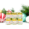 Jars of honey with Christmas-themed labels surrounded by festive ornaments on a white background