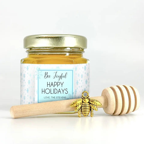 Jar of honey with a gold lid and a honey dipper on a white background