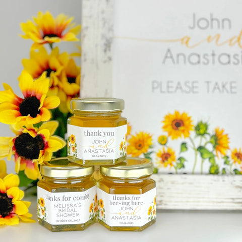 Three small jars with personalized labels surrounded by sunflowers and a decorative sign.