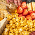 Platter with utah honey popcorn, strawberries, crackers, and a jar of honey.