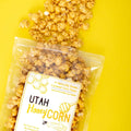 Open bag of honey corn spilling out onto yellow background. Label on bag says Utah Honey Corn