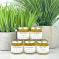 Jars of honey stacked with a plant in the background