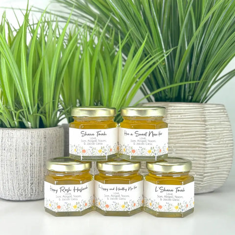 Jars of honey stacked with a plant in the background