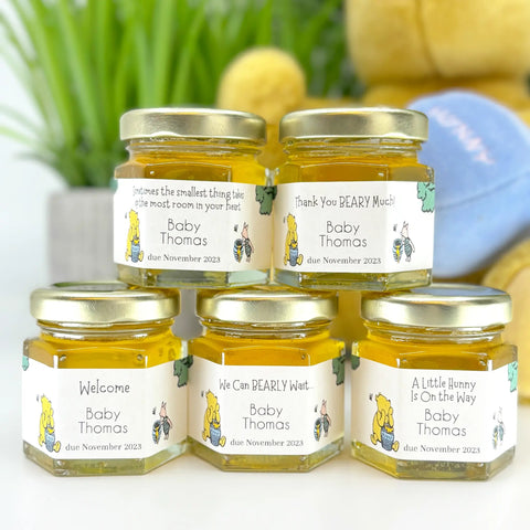 Five small jars with personalized labels on a white surface, with a blurred background.