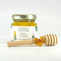 Jar of honey with a personalized label, honeycomb charm, and wooden honey dipper on a white background