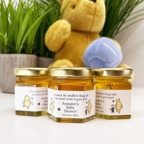 Three small jars with labels in front of a teddy bear and plants