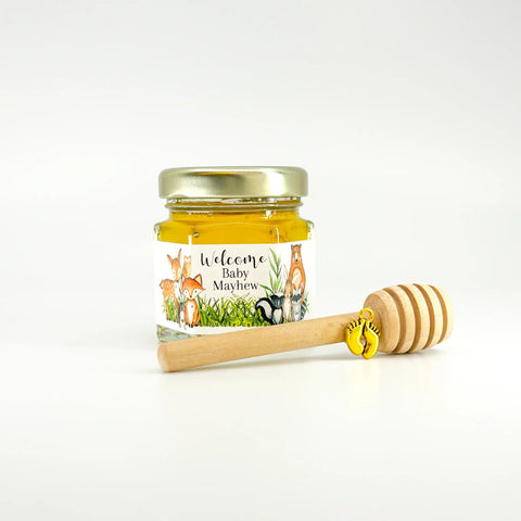 Jar of honey with a personalized label and wooden honey dipper on a white background