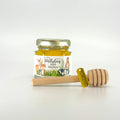 Jar of honey with a personalized label and wooden honey dipper and gold thank you charm on a white background