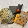 Beeswax wraps with cheese and a tomato on a speckled countertop