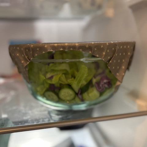 Glass bowl with sliced cucumbers and lettuce covered with beeswax wrap