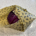 Purple cabbage wrapped in yellow beeswax wrap on a speckled countertop