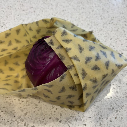 Purple cabbage wrapped in yellow beeswax wrap on a speckled countertop