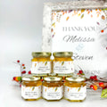 Jars of honey with personalized labels in front of a 'Thank You' sign and fall decorations.