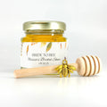 Jar of honey with a personalized label and a honey dipper on a white background