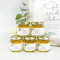 Five jars of honey with personalized labels on a white surface.