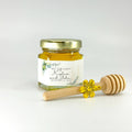 Jar of honey with a custom label and wooden honey dipper on a white background