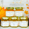 Jars of honey with personalized labels on a decorative background
