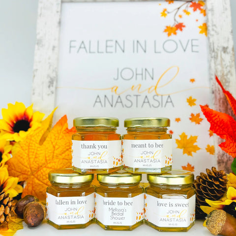 Jars of honey with personalized labels in front of a 'Fallen in Love' sign with autumn leaves.