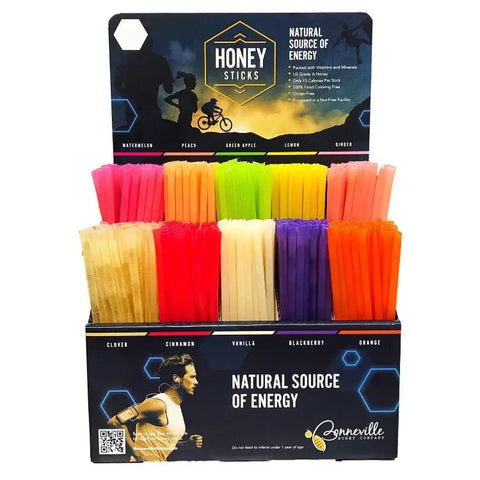 Display of colorful honey sticks with 'Honey Sticks' packaging on a white background