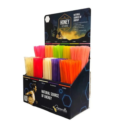 Display of colorful honey sticks in a branded box with 'Honey Sticks' packaging.