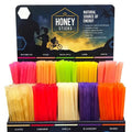 Assorted colorful honey sticks in a display box with 'Honey Sticks' branding.