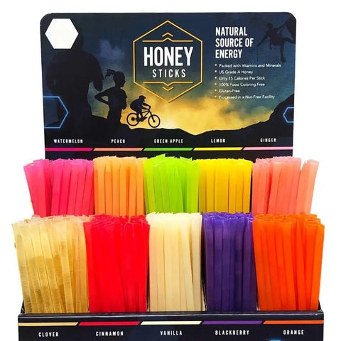 Assorted colorful honey sticks in a display box with 'Honey Sticks' branding.